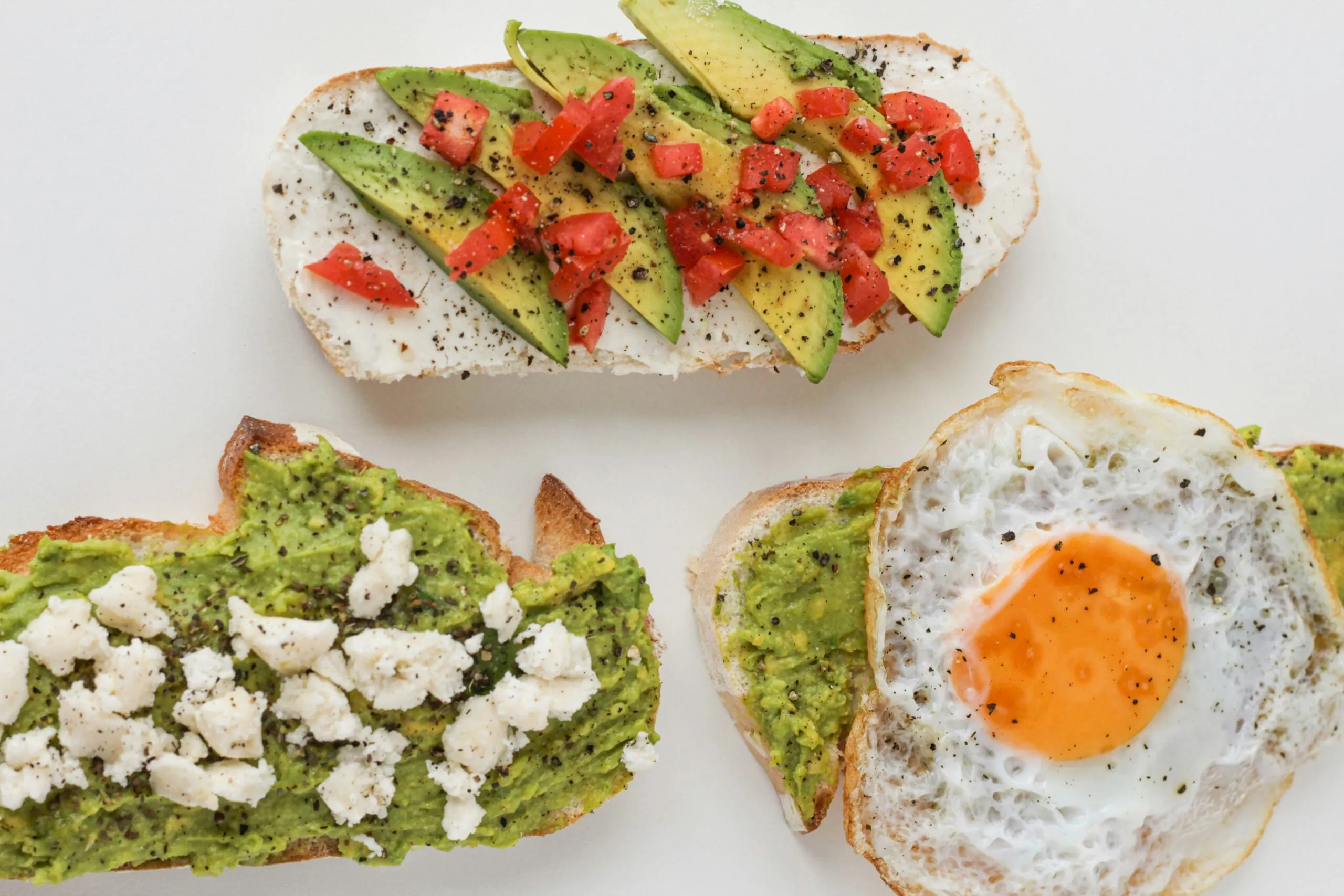 3 avocado toasts avec un oeuf au plat, de la feta et des tomates.